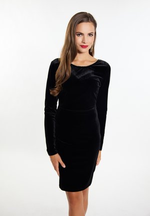 Schwarzes Samtkleid mit langen Ärmeln, knielang, mit rundem Ausschnitt und einem dezenten Glanz. Glatte Textur mit einer taillierten Silhouette.