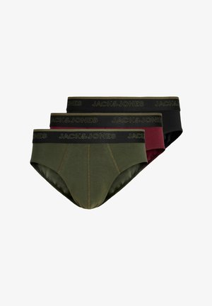 Noor mees lühikeste blondide juustega, seljas burgundia värvi Jack & Jones aluspüksid, seisab ühevärvilise heleda tausta ees näoga ettepoole.