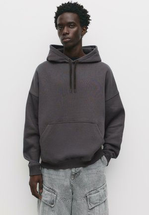 Gray hoodie with a drawstring hood, kangaroo pocket, and ribbed cuffs, paired with light gray cargo shorts featuring large pockets.