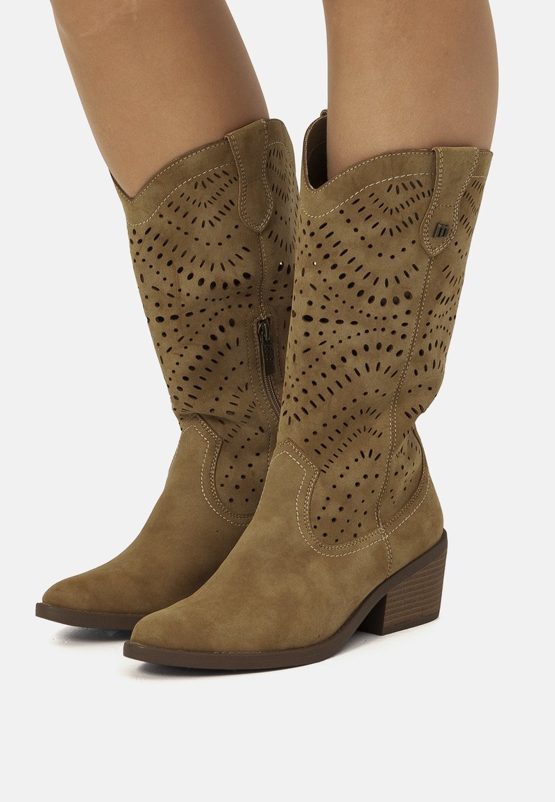 Botas de cowboy de ante marrón con diseño perforado, punta afilada, tacón bajo apilado y costuras en contraste. Cierre de cremallera en el lateral.