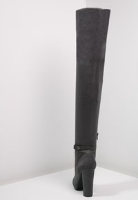 Bota gris por encima de la rodilla hecha de suave ante, con punta redonda, tacón alto cuadrado y correa en el tobillo con detalle de hebilla metálica.