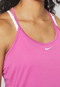 Fuchsia Sporttop mit glatter Textur, featuring weiße verstellbare Träger und ein kleines weißes Nike-Logo auf der Brust.
