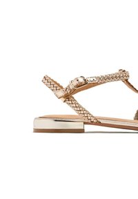 Le sandali piatti color oro rosato presentano un design con fascetta intrecciata, una fibbia regolabile e un tacco blocco metallico elegante. Soletta in pelle liscia.