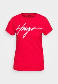 Camiseta de algodón roja con un gran logo blanco "Hugo" impreso en el frente, escote redondo y mangas cortas.