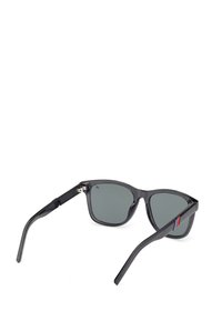 Occhiali da sole neri in plastica con lenti scure, caratterizzati da una forma rettangolare, montatura sottile e un piccolo accento multicolore su una delle astine.