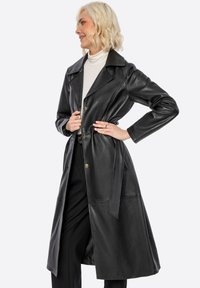 Černý kožený trenčkot s výstřihem, páskem v pase a zlatými knoflíky, disponující dlouhými rukávy a středně dlouhým střihem.