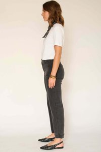 Jean en denim noir avec une taille ajustée et une coupe droite, associé à un t-shirt blanc ajusté et des chaussures slingback noires avec des découpes circulaires.