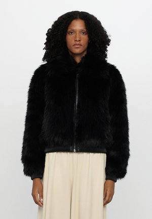 Veste bomber en fausse fourrure noire avec un col rond, fermeture éclair à l'avant et poignets côtelés. Texture douce et design volumineux, adaptée pour les temps frais.