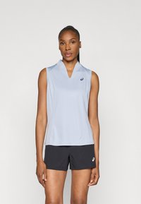 Αμάνικο αθλητικό τοπ σε ανοιχτό μπλε χρώμα με σχέδιο V και λεπτομέρεια λογότυπου στο στήθος, σε συνδυασμό με μαύρες βερμούδες. Λείο υλικό.