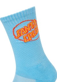 Hellblaue Socken mit einem gerippten Bündchen zeigen in der Mitte ein kräftiges, orange-gelbes "SANTA CRUZ"-Logo. Weiche, gestrickte Textur, mittlere Schafthöhe.
