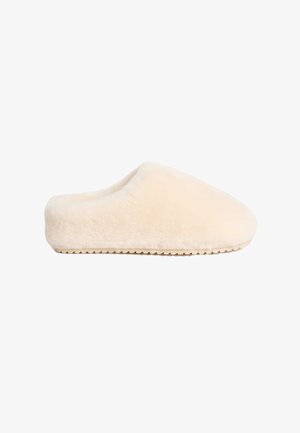 Beige, weiche, flauschige Hausschuhe mit einer soliden flachen Sohle und abgerundeter Zehe, die ein nahtloses Design und eine samtige Textur aufweisen.