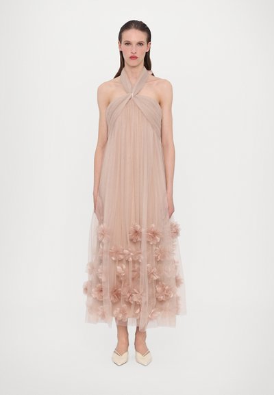 Un vestito senza maniche, di un leggero taupe, lungo fino al pavimento, con pieghe verticali, caratterizzato da fiori di stoffa lungo l'orlo e un design con collo halter annodato.