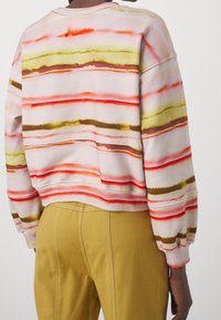 Sudadera con rayas horizontales abstractas en rosa, amarillo, naranja y marrón, con un corte holgado y puños acanalados.