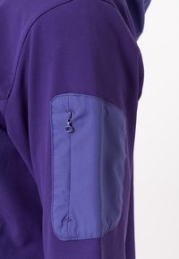Lila Jacke aus glattem Stoff. Verfügt über eine mit Reißverschluss verschließbare Tasche am Ärmel, aus kontrastierendem, helllila Material.