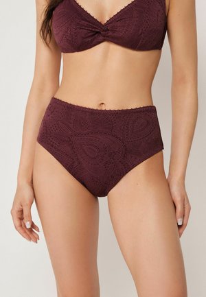 Femme portant un bas de bikini taille haute et un soutien-gorge assortis bordeaux avec un motif Paisley complexe, montrée des épaules aux cuisses.
