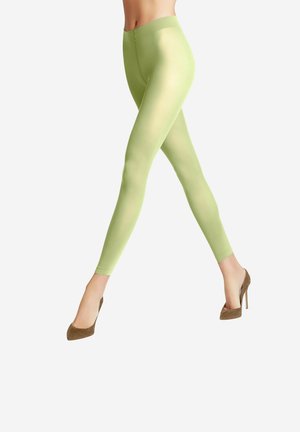 Grüne Leggings aus einem glatten, dehnbaren Stoff. Sie haben einen hohen Taillenbund und ein figurbetontes Design, kombiniert mit braunen High Heels.