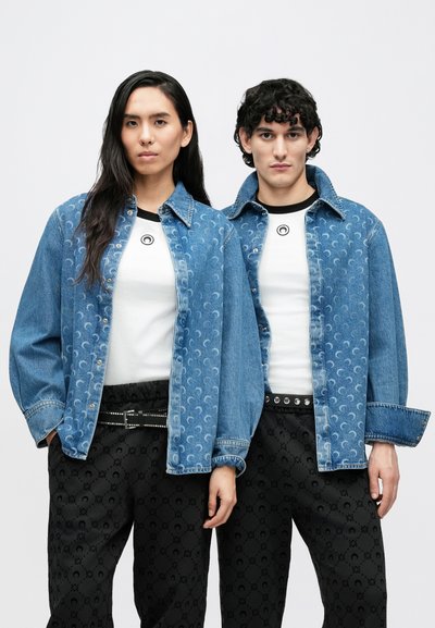 Világoskék farmerdzsekik gombos záródással, finom félhold mintával. Fehér pólók, fekete mintás nadrágok szegecselt övvel.