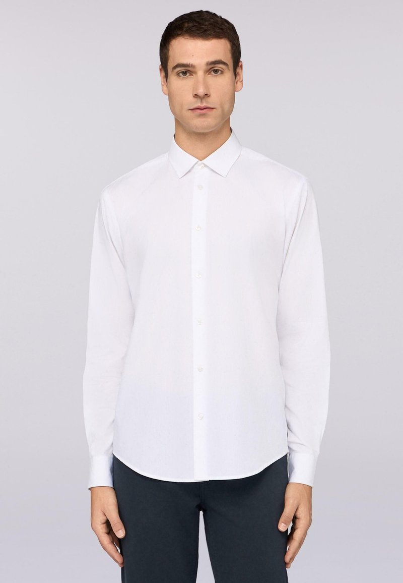 Witte langlopende, knopsluiting overhemd met een klassieke kraag, gladde textuur en ronde zoom, gecombineerd met donkergekleurde broek.