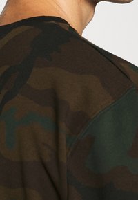Sweatshirt met camouflagepatroon in tinten donker groen en bruin, gemaakt van een gestructureerde, zachte stof en met een ronde hals.