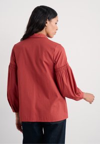 Roodachtig shirt met een kraag, smockballoonmouwen en een gestructureerd gestreept patroon. Casual fit en rechte zoom.