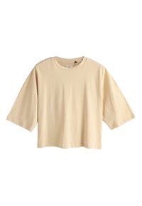 T-shirt oversize beige à manches courtes avec col rond et épaules tombantes, présenté sur un fond blanc uni.