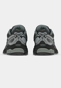 Černé a šedé běžecké boty s síťovaným svrškem, texturovanými detaily, polstrovaným límcem a kontrastním vzorem podešve, zobrazené ze zadní strany.