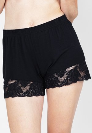 Zwarte katoenen shorts met een elastische tailleband, voorzien van een kantafwerking aan de zoom. Het kant heeft een bloemenpatroon en geschulpte randen.