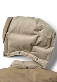 Beige Kapuze aus Cord mit einem glatten Obermaterial, ausgestattet mit Druckknöpfen an der Unterseite und einem strukturierten Stoff. Das Design umfasst abgerundete Akzente.