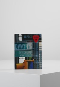 Quaderno con un design di insegna stradale, testo blu e verde, logo rosso di Strellson e una superficie liscia e lucida.
