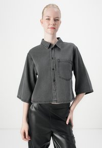 Korte mouwen, grijze denim shirt met een knoopsluiting aan de voorkant, kraag en borstzak. Cropped ontwerp met een licht gestructureerde afwerking.