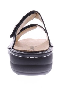 Black sandal with three adjustable straps, cork footbed, and textured platform. White stitching accents the edge of the sole.