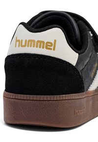 Sneaker in pelle scamosciata nera con logo bianco e oro sul tallone, suola intermedia strutturata e suola esterna in gomma con motivo a diamante.