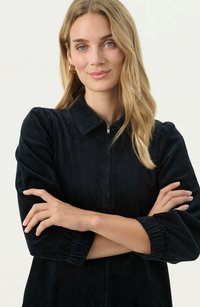 Abito in velluto a coste nero con zip frontale, colletto e maniche arricciate, che presenta una morbida texture a righe.