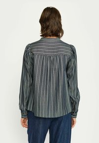 Blusa a righe di colore grigio scuro con sottili strisce bianche e colorate. Presenta maniche a sbuffo, un orlo arrotondato e un design della schiena arricciato.