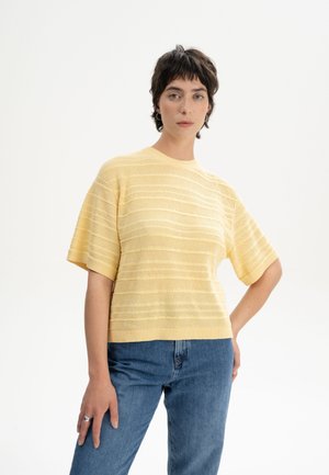 Geel gebreid pullover met korte mouwen en gestreepte textuur, gecombineerd met blauwe denim jeans. De pasvorm is relaxed en casual.