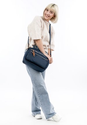 Sac crossbody navy avec une surface texturée, deux compartiments zippés et des accents en cuir marron. Design léger et compact.