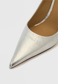 Spids tå høje hæle sko i metallisk sølvlæder med en krøllet tekstur, der har en glat indvendig foring og sort ydersål.
