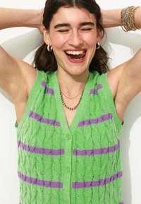 Pull sans manches vert en tricot torsadé avec des rayures violettes, bouton sur le devant et tissage texturé.