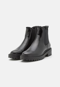 Bottines en cuir noir avec panneaux élastiques sur les côtés, bout rond, semelle en caoutchouc texturée et doublure en fausse fourrure au niveau de l'ouverture.