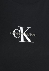 Czarny bawełniany t-shirt z białym logo "CK" i tekstem "CALVIN KLEIN JEANS" w kolorze srebrnym, z klasycznym dekoltem okrągłym.