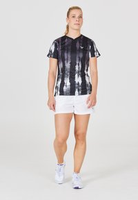 Sort-hvid stribet atletisk skjorte med korte ærmer, parret med hvide shorts og hvide atletiske sko med lilla accenter.