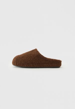 Brune, fluffy tøfler med avrundet tå, laget av mykt, teksturert materiale, med en slip-on design og lav profil for enkel slitasje.