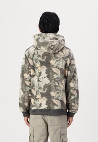 Felpa in pile con cappuccio, caratterizzata da un motivo camouflage nei colori verde, beige e grigio. Polsini e orlo elastici, texture morbida.