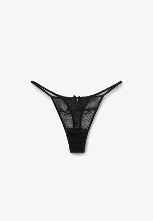 String noir en dentelle avec des panneaux en mesh transparent et un motif floral, des fines bretelles et un petit nœud en accent à l'arrière.