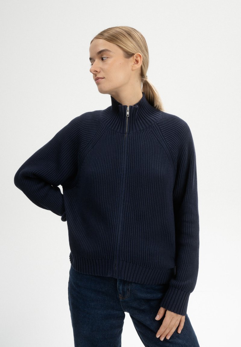 Marineblauer gerippter Pullover mit hohem Kragen und durchgehendem Reißverschluss. Verfügt über Raglanärmel und eine lockere Passform. Die strukturierten Materialien sorgen für visuelles Interesse.