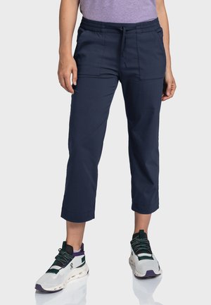 Marineblaue, kurze Hosen mit elastischem Bund, zwei vorderen Taschen und einer glatten Oberfläche, kombiniert mit weißen und grünen Sportschuhen.