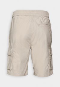 Pantalones cortos cargo beige con cinturilla elástica, bolsillos laterales con solapa y un bolsillo trasero de ojal, mostrados desde la parte posterior sobre un fondo liso.