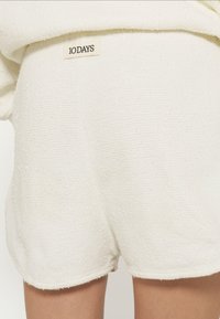 Pantaloni corti in spugna bianca con superficie testurizzata, dotati di un'etichetta cucita che recita "10 DAYS" sulla cintura.