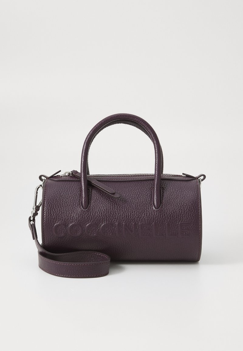 Sac à main en cuir violet avec deux anses supérieures, une fermeture éclair et une bandoulière ajustable. Présente le nom de la marque en relief. Fini texturé.