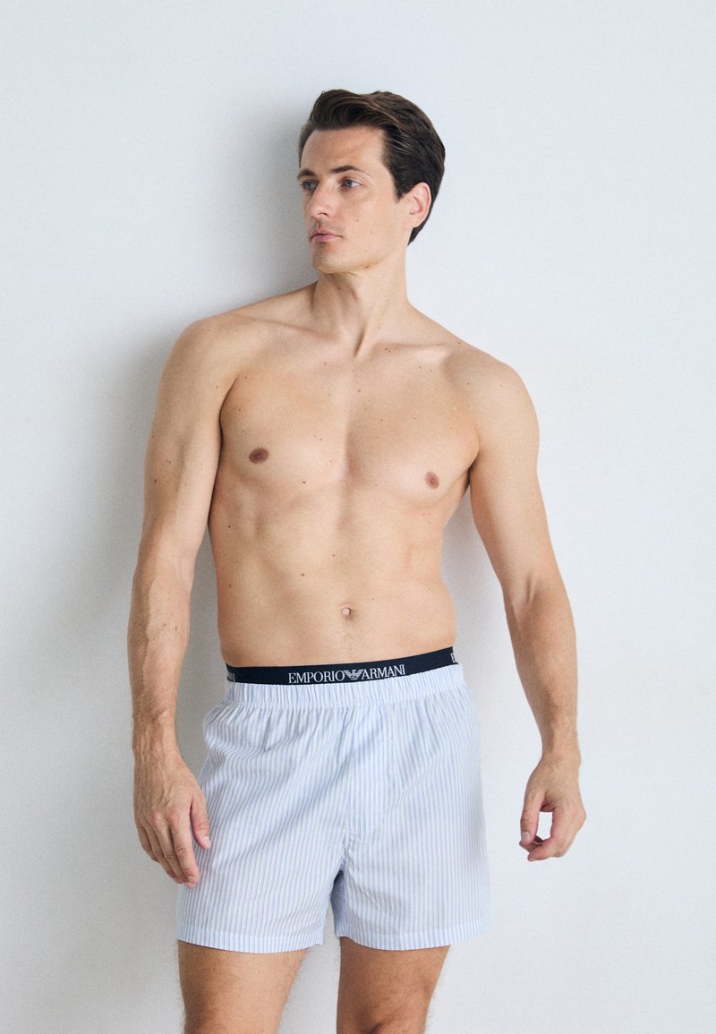 Boxeri cu dungi albastre și albe, cu un brâu elastic negru ce prezintă logo-ul "Emporio Armani". Material moale cu o croială liberă.